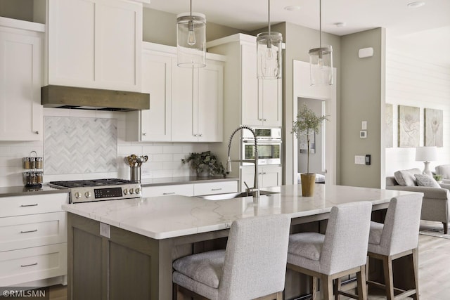 4104 Osprey Ct, Prior Lake, MN 55372 - kitchen featuring decorative backsplash, a kitchen island with sink, white cabinetry, a sink, and light stone countertops