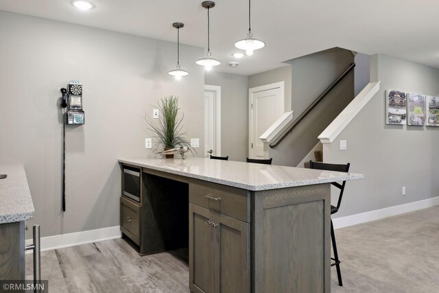 4104 Osprey Ct, Prior Lake, MN 55372 - kitchen with a peninsula, a kitchen breakfast bar, baseboards, stainless steel microwave, and light stone countertops