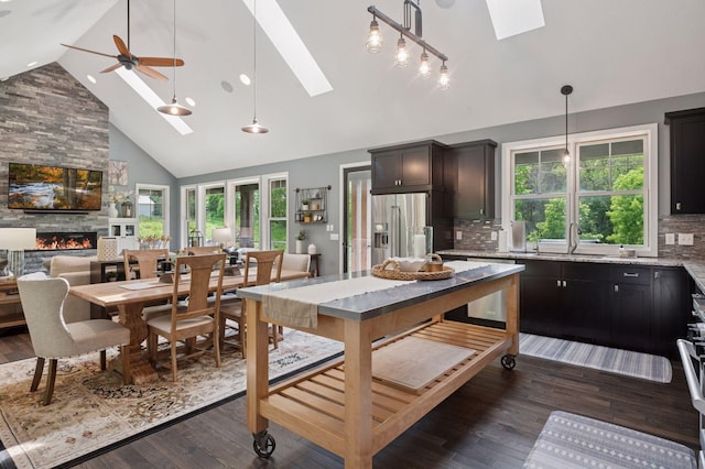 1701 Retreat Cir, Minnetrista, MN 55364 - dining space featuring a skylight, high vaulted ceiling, a fireplace, a ceiling fan, and dark wood-style flooring