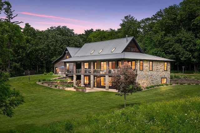 1701 Retreat Cir, Minnetrista, MN 55364 - back of property at dusk featuring a patio, a lawn, stone siding, and a balcony