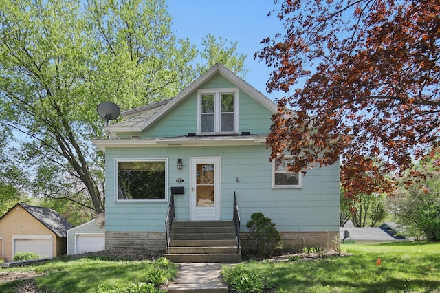 733 1st St SW, Faribault, MN 55021 - bungalow with entry steps, a garage, a front yard, and an outbuilding