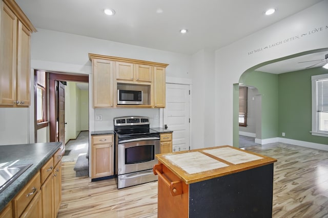 733 1st St SW, Faribault, MN 55021 - kitchen featuring appliances with stainless steel finishes, light wood-style flooring, arched walkways, a kitchen island, and recessed lighting