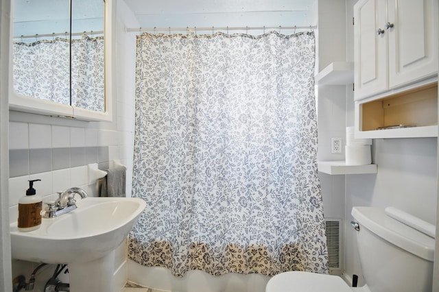 733 1st St SW, Faribault, MN 55021 - bathroom with toilet, backsplash, tile walls, and shower / tub combo