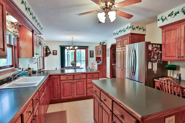 127 County Rd W, Pleasant Valley Twp, WI 54022 - kitchen with a sink, freestanding refrigerator, a textured ceiling, brown cabinets, and a peninsula