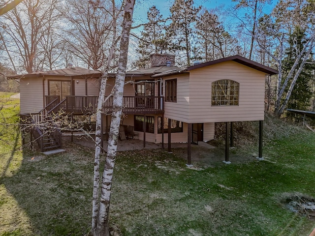 back of house featuring a chimney, a wooden deck, stairway, and a yard