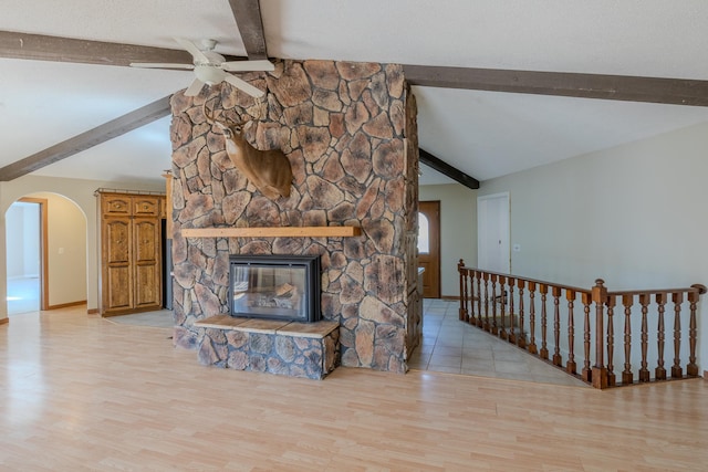 unfurnished living room featuring ceiling fan, arched walkways, wood finished floors, and baseboards