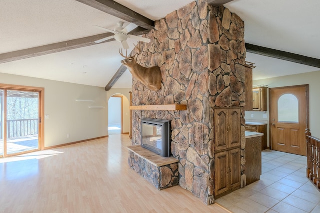 unfurnished living room featuring a ceiling fan, arched walkways, healthy amount of natural light, and a fireplace
