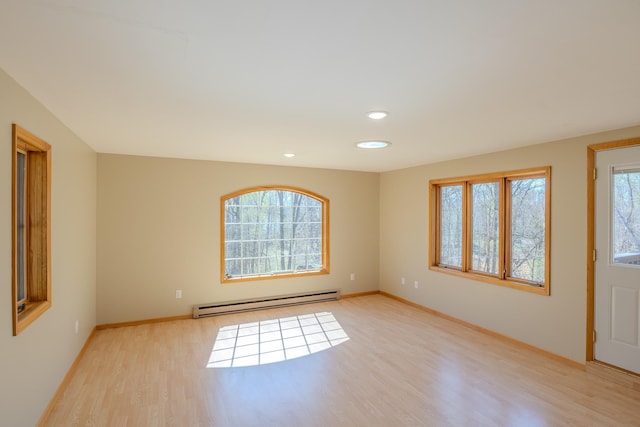 empty room featuring a baseboard heating unit, light wood-style floors, baseboards, and recessed lighting