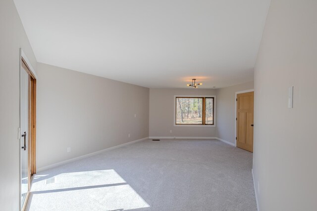 unfurnished room featuring light carpet and baseboards