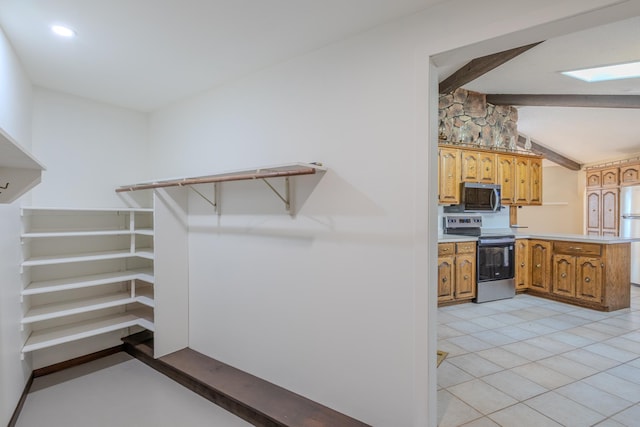 kitchen featuring stainless steel appliances, a peninsula, light countertops, and brown cabinets