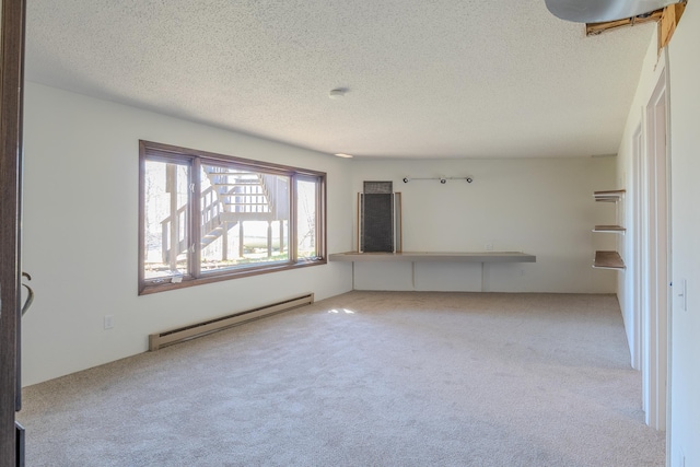 empty room featuring a baseboard heating unit, carpet, and a textured ceiling