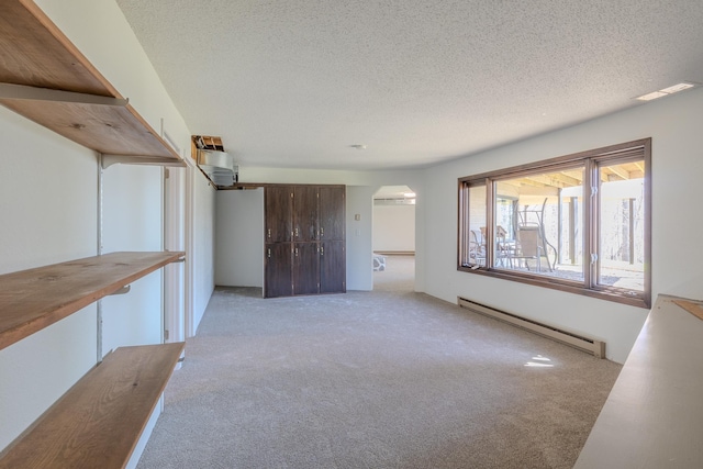 unfurnished living room with a baseboard radiator, light colored carpet, arched walkways, and a textured ceiling
