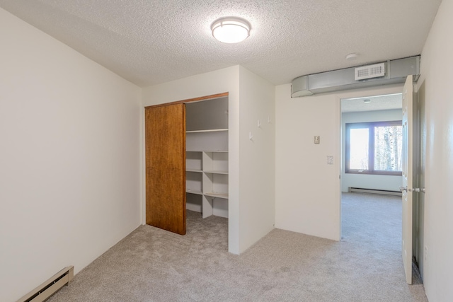 unfurnished bedroom featuring a baseboard radiator, carpet, a textured ceiling, and a closet