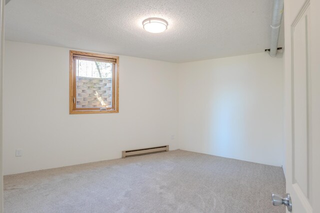 carpeted empty room featuring a baseboard radiator and a textured ceiling