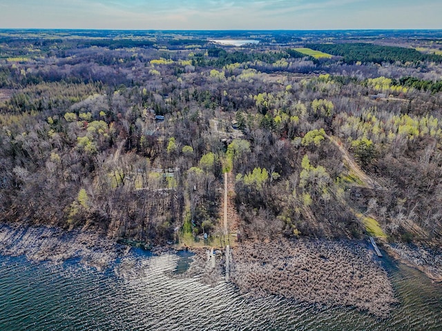aerial view of property and surrounding area featuring a heavily wooded area and a large body of water