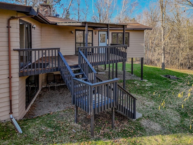 back of property featuring stairway, a wooden deck, a chimney, and a yard