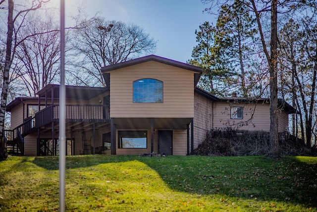 back of property with a deck, a yard, and stairs