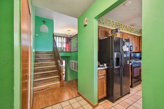 6522 Kilmer Ln N, Maple Grove, MN 55369 - kitchen featuring black appliances, a textured ceiling, light tile patterned flooring, brown cabinets, and a chandelier