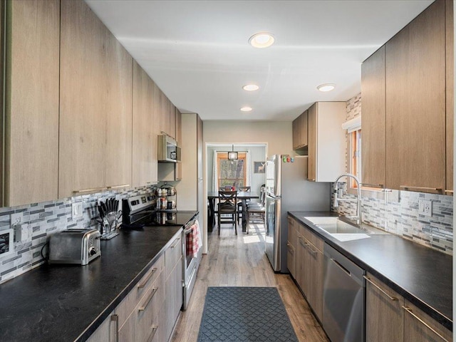 15921 Eaglewood Dr, Bay Lake Twp, MN 56444 - kitchen featuring appliances with stainless steel finishes, a sink, dark countertops, tasteful backsplash, and light wood-type flooring