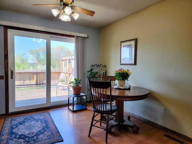 dining space featuring wood finished floors, a ceiling fan, a textured ceiling, and baseboards