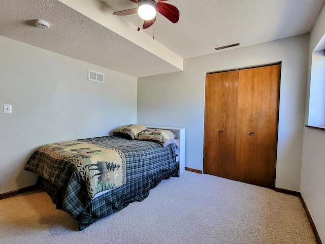carpeted bedroom featuring a closet, baseboards, a ceiling fan, and a textured ceiling