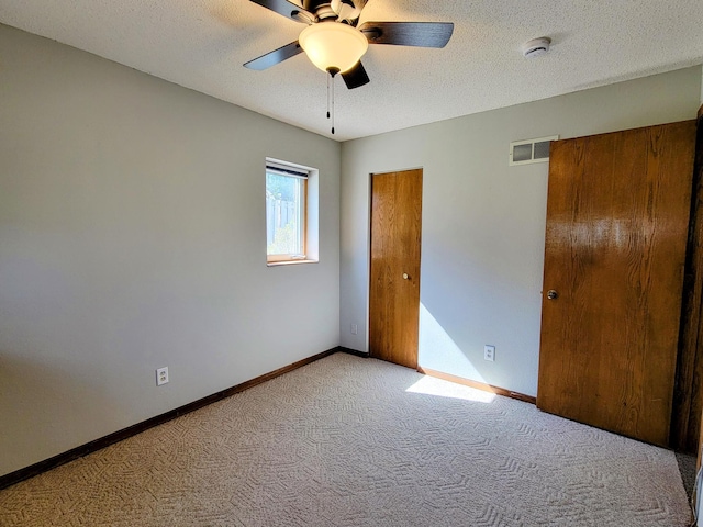 unfurnished bedroom featuring carpet, baseboards, a textured ceiling, and a ceiling fan