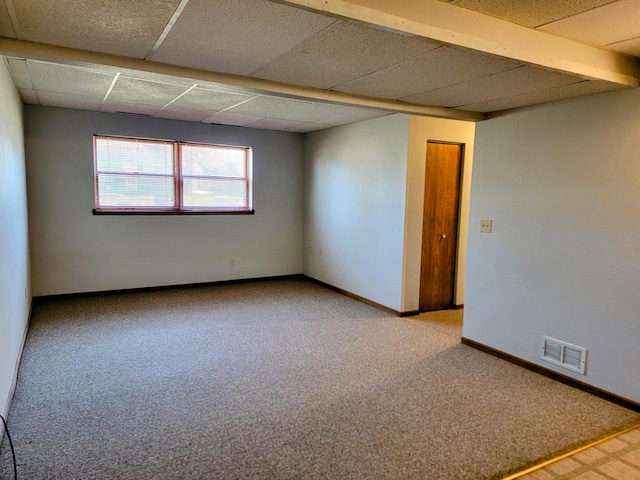 empty room with carpet flooring, a drop ceiling, and baseboards