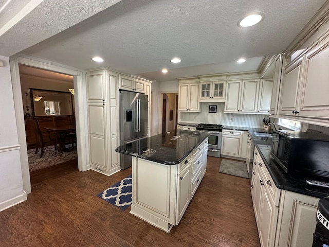 kitchen with stainless steel appliances, dark wood-style flooring, a textured ceiling, a kitchen island, and recessed lighting