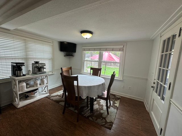 dining room featuring a textured ceiling, wood finished floors, and baseboards