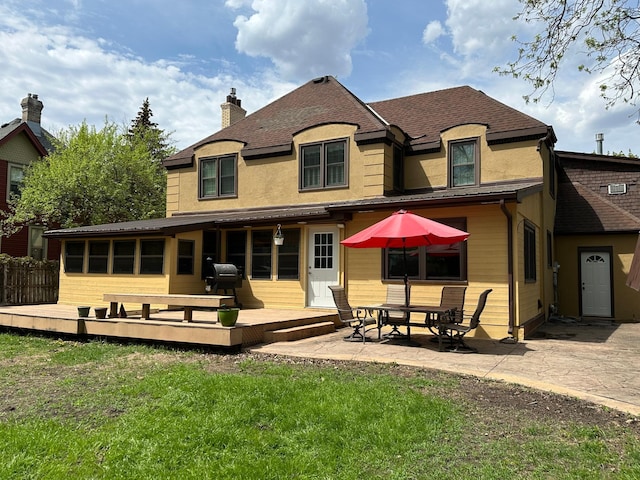 back of property featuring a deck, a yard, a patio, and stucco siding