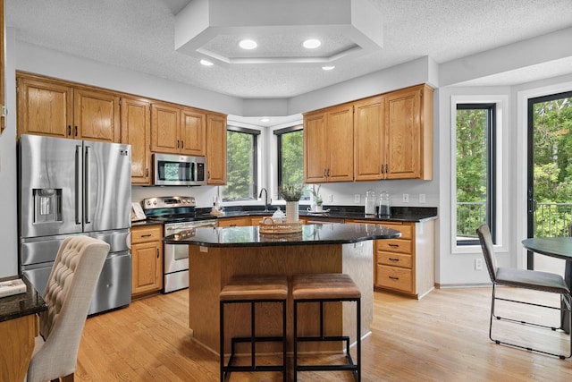 4255 Wexford Way, Eagan, MN 55122 - kitchen featuring stainless steel appliances, light wood-style flooring, a breakfast bar area, a center island, and a textured ceiling