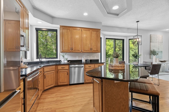 4255 Wexford Way, Eagan, MN 55122 - kitchen with stainless steel appliances, a kitchen breakfast bar, a textured ceiling, a center island, and light wood-style floors