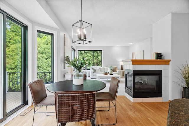 4255 Wexford Way, Eagan, MN 55122 - dining area with light wood-style flooring, a tile fireplace, and a chandelier