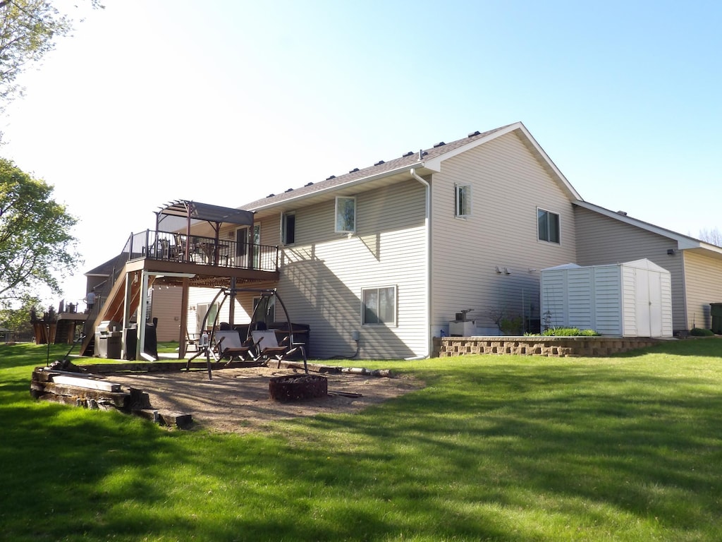 back of house with a wooden deck, a storage unit, a lawn, stairway, and an outbuilding