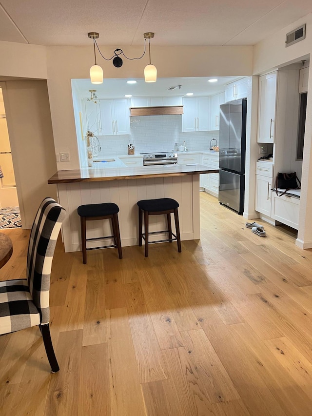 kitchen featuring stainless steel appliances, light wood-style flooring, a peninsula, and a sink