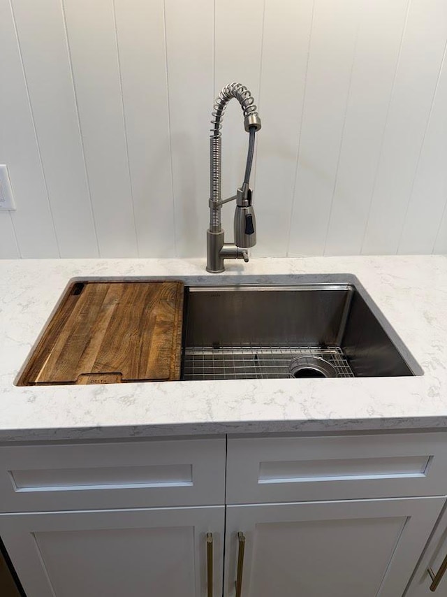 kitchen view of gray cabinetry, light stone countertops, and a sink