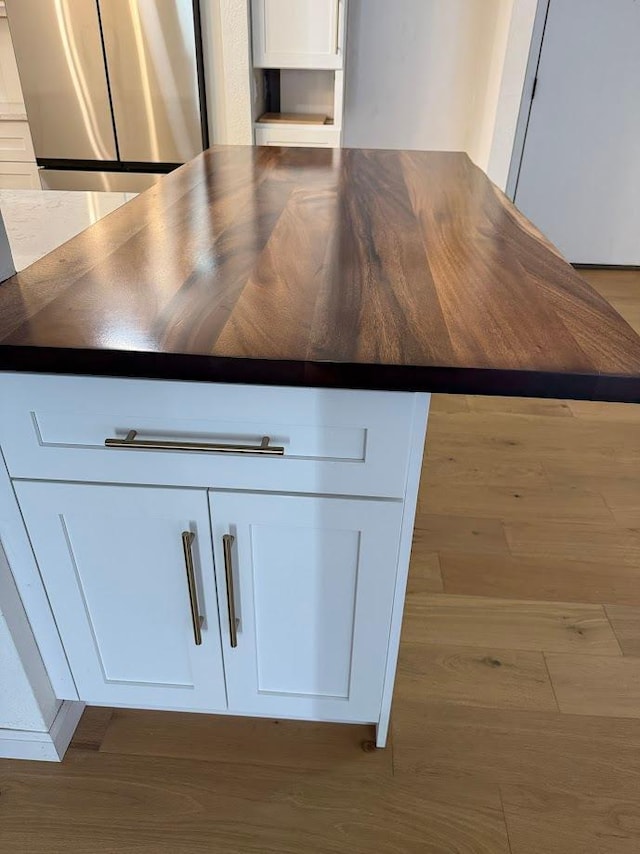 kitchen view of dark countertops, white cabinets, and wood finished floors
