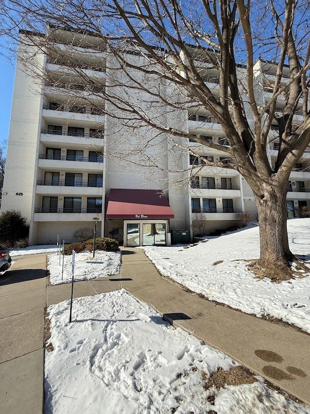 snow covered building with a view of apartment building / complex
