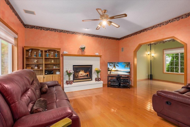 9230 Cheney Trl, Inver Grove Heights, MN 55076 - living room with arched walkways, wood finished floors, ceiling fan, a brick fireplace, and baseboards