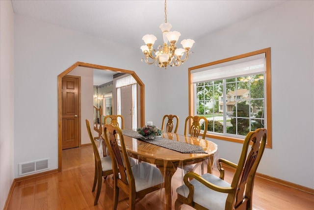 9230 Cheney Trl, Inver Grove Heights, MN 55076 - dining space featuring light wood-type flooring, a chandelier, baseboards, and arched walkways