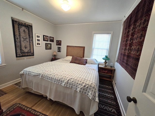 bedroom featuring baseboards, wood finished floors, and crown molding