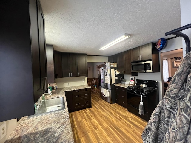 7424 Ely Lake Dr, Fayal Twp, MN 55734 - kitchen with stainless steel appliances, light wood-style flooring, dark brown cabinetry, a textured ceiling, and light stone counters