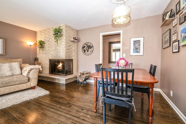 dining room with wood finished floors, a brick fireplace, and baseboards