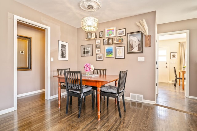 dining area featuring wood finished floors, a chandelier, and baseboards