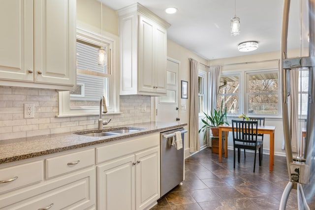 kitchen featuring dishwasher, a sink, decorative backsplash, and baseboards