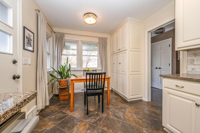 dining space with dark stone finish floors and baseboards