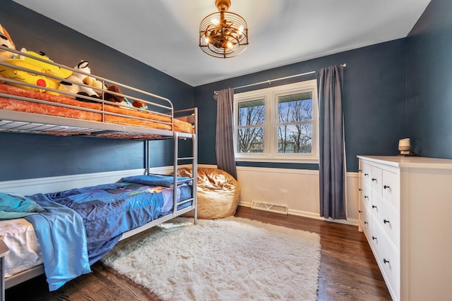 bedroom featuring wood finished floors, baseboards, and a chandelier
