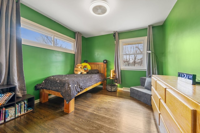 bedroom featuring wood finished floors, multiple windows, and baseboards