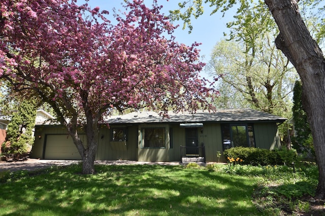 single story home with a garage, a front yard, and concrete driveway