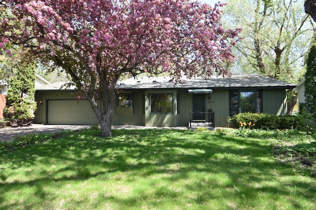 ranch-style house featuring an attached garage, a front yard, and driveway